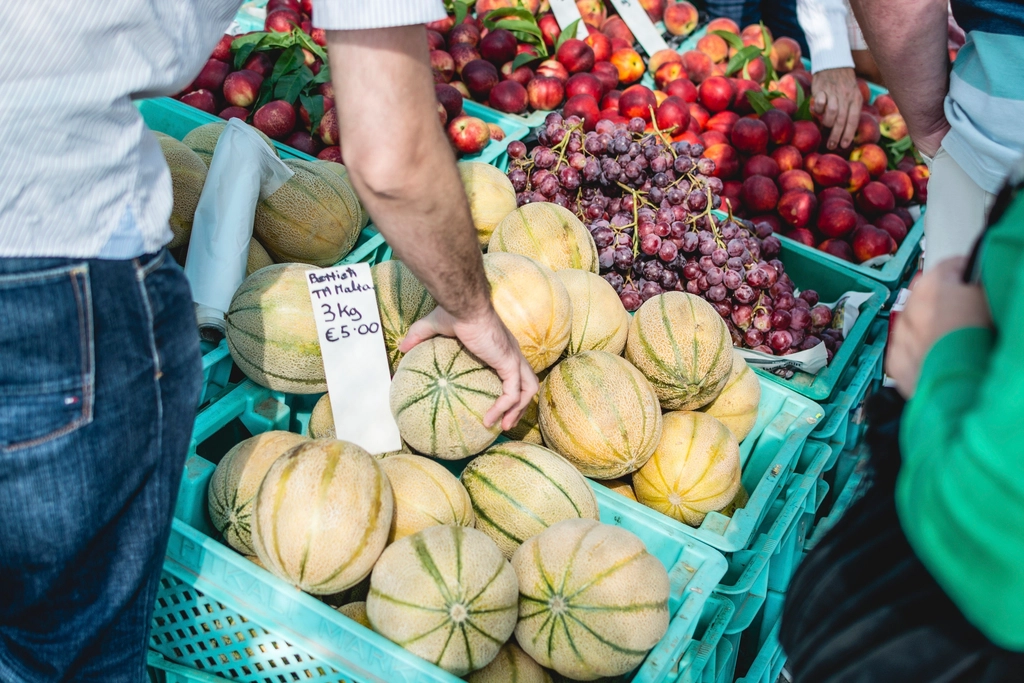 Hands passing fresh vegetables across a market stall