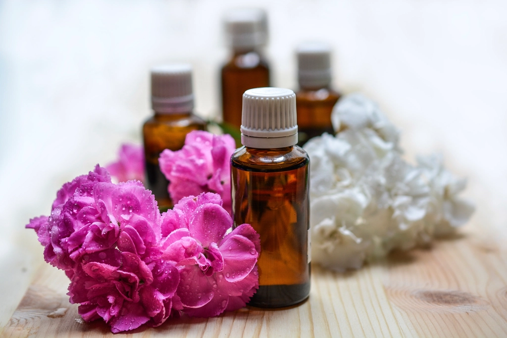 Amber essential oil bottles beside fresh pink flowers